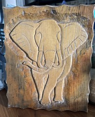 wooden plaque featuring a relief carving of an elephant