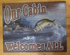 Our Cabin Welcomes All (Fish Theme) Metal Sign by Desperate Enterprises